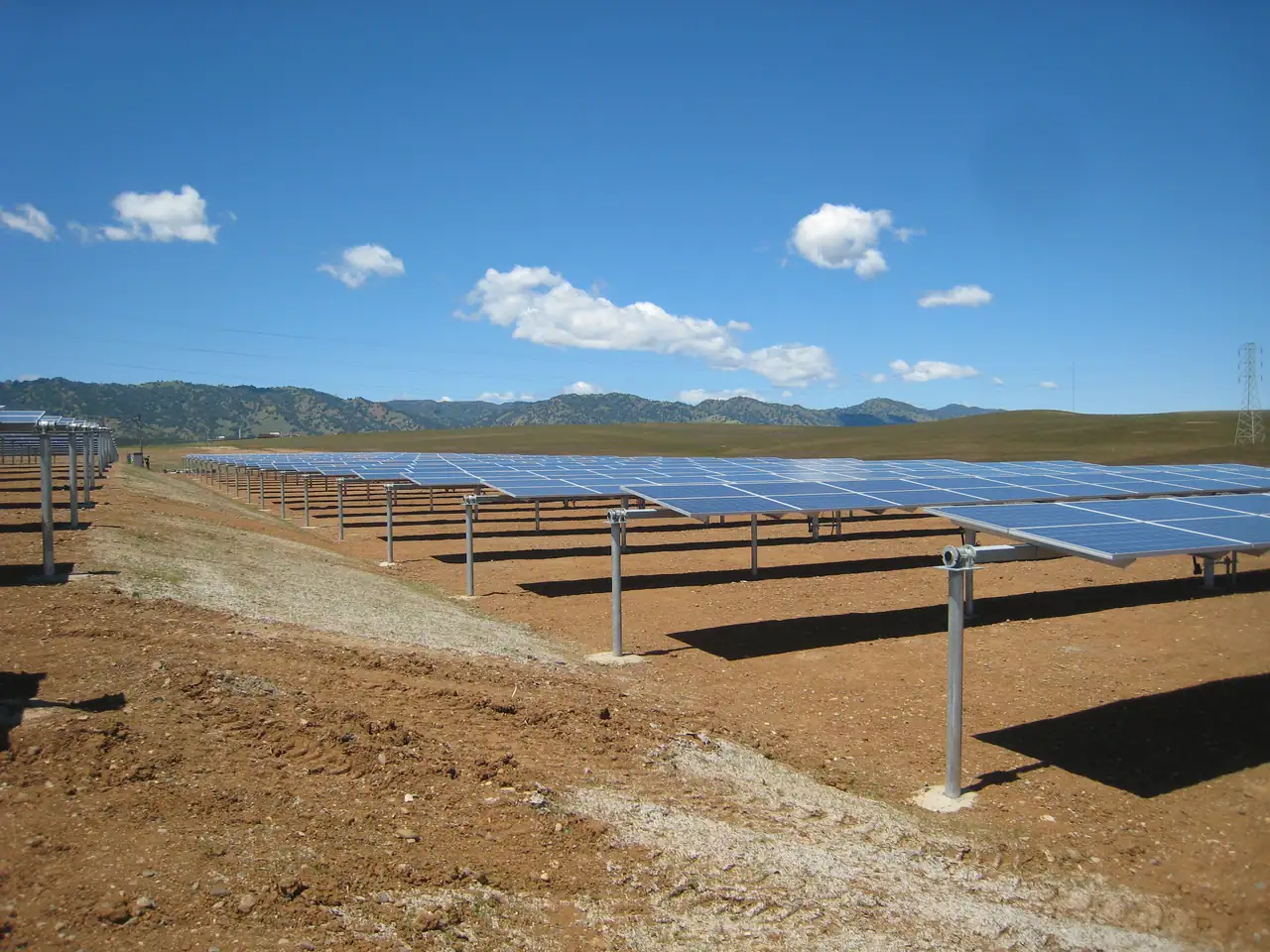 Rows of single-axis solar trackers under a blue sky
